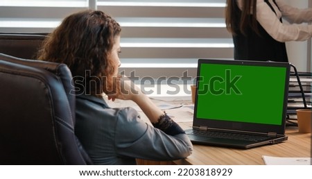 Business woman or female freelancer watching a webinar on green screen chroma key laptop. Girl looking at green screen laptop computer watching movie, video content.