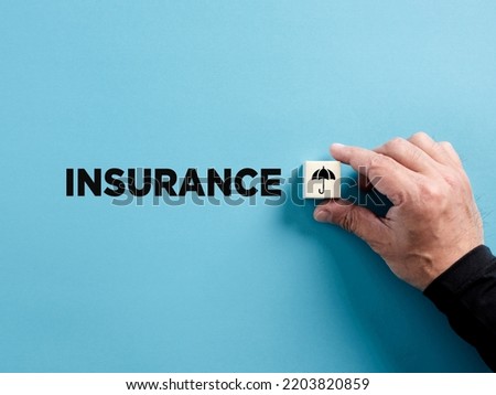Male hand puts the wooden cube with insurance symbol next to the word insurance. Insurance concept.