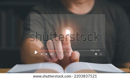 Businessman or student playing the video for learning new technology or music. Finger pointing at play button on virtual screen and a book is on the table. Studying or learning concept. Royalty-Free Stock Photo #2203837521