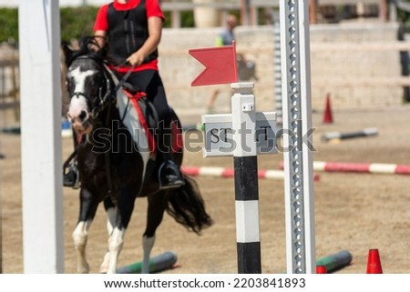 Close up on Start Signage on Blurred girl that rides a Pony during Pony Game Competition at the Equestrian School