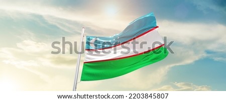 Uzbekistan national flag waving in beautiful sky.