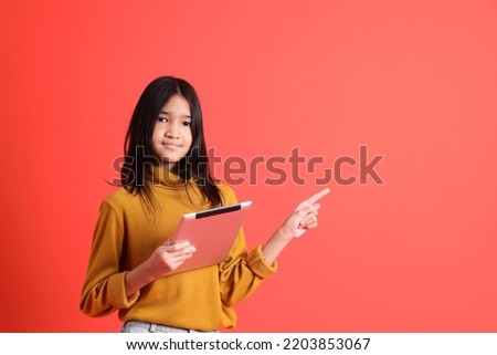 The young Asian girl with yellow shirt on the orange background.