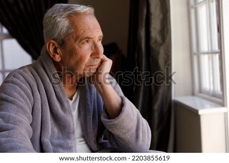 Senior caucasian man spending time at home, sitting, looking away and thinking. isolating during coronavirus covid 19 quarantine lockdown. Royalty-Free Stock Photo #2203855619
