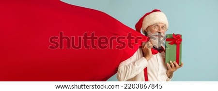 Santa Claus with gift and bag on light blue background. Banner for design