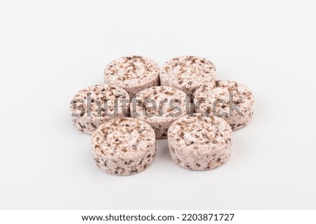 Heap of pink pills or vitamine tablets on a white background