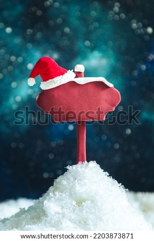 Wooden pointer and Santa's hat on the background of the night starry sky. Space for text, mockup, blank. Christmas background. 