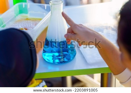 An adult shows a child a chemical reaction in a flask