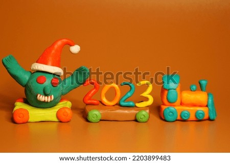 A toy train with the number 2023 and a coronavirus figurine. Festive event, Christmas and New Year. A symbol of the advent of holidays.