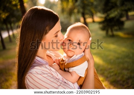 Portrait of lovely lady mom cuddle kiss beloved toddler infant boy looking in camera outdoors spring season weekend