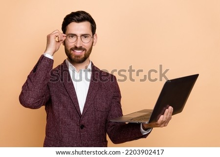 Photo of reliable representative young businessman working in wireless netbook isolated on beige color background