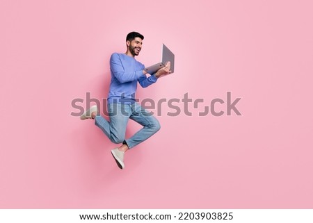 Full length photo of funny pretty guy dressed blue pullover jumping high typing modern device isolated pink color background Royalty-Free Stock Photo #2203903825