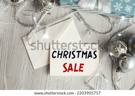 CHRISTMAS SALE text on the plate along with the envelope, against the background of the New Year's decor. Christmas background with decorations from balls and garlands. 
