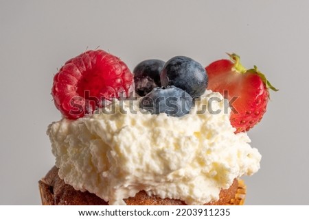 Close-up of top of appetizing muffin with delicious vegan cream and fresh berries . Place for your text. Sweet concept. Excellent image for dessert banners and advertisements. Desert background. 