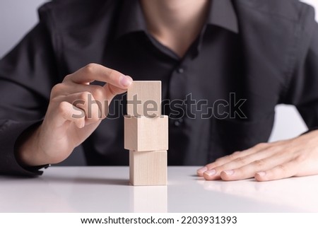 man build a tower by using three  blank wooden cube on table. Mockup for letters, symbol, picture text, word, idea and concept.