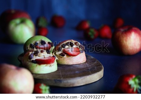 Apple monster mouths open wide with strawberry tongues and raisin teeth. Filled with peanut butter. Selective focus with blurred foreground and background. 