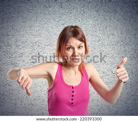 Young redhead making a good-bad sign over textured background 