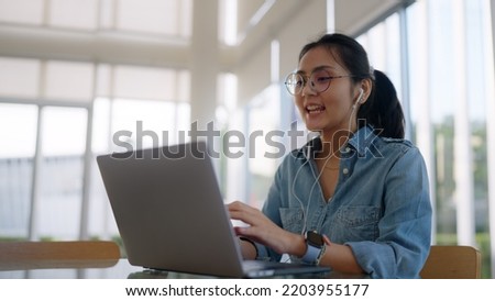 Asia people young girl relax smile video call talk on laptop sit learn study online class reskill career upskill job hybrid workation at modern coworking workspace share office in future workforce. Royalty-Free Stock Photo #2203955177