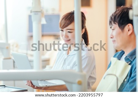 Asian female dental hygienist and patient teaching tooth brushing