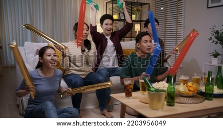 Group of young adult friend man and woman asia people sit at sofa couch joy night party fun game FIFA world cup live TV at home eat snack bowl drink beer bottle glass jump mad happy win exult face. Royalty-Free Stock Photo #2203956049