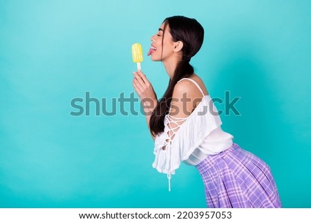 Profile side photo of playful cute lady want eat new frozen yogurt pop lick tongue isolated cyan color background