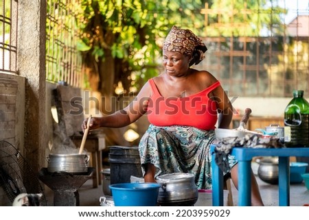 image of african woman stirring a pot- cooking concept Royalty-Free Stock Photo #2203959029