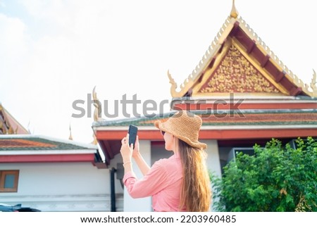 Backpack tourist woman take photo with samrtphone while travelin buddha temple sightseeing in Bangkok Thailand