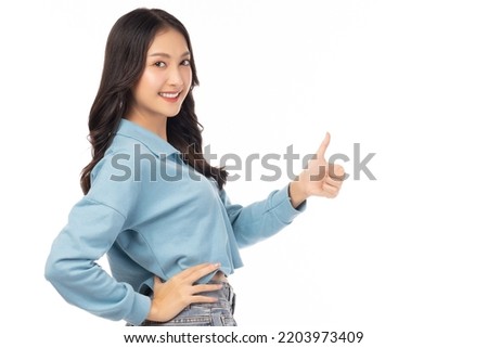 Smiling beautiful young woman showing thumbs up isolated on white background studio Young happy asian girl looking at camera show thumb up gesture with arm akimbo Beautiful lady feeling happiness