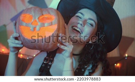 A girl in a creepy costume with a Jack-o'-lantern poses for the camera on Halloween