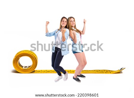 Lucky girls around tape measure over white background