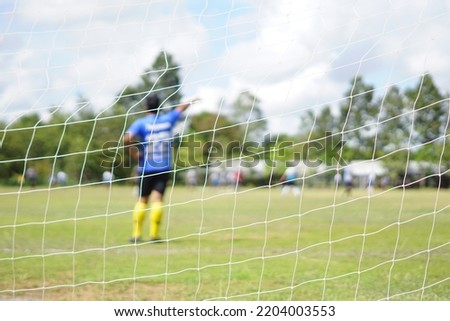 Football goal net, soft focus on the goalkeeper.