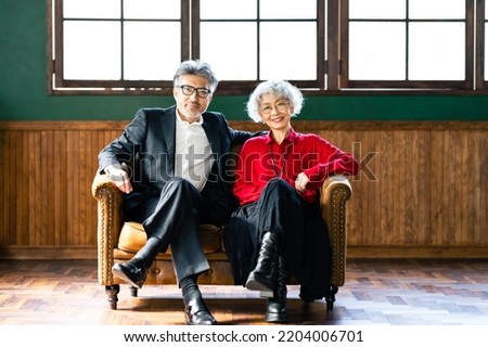 Asian elderly couple sitting on sofa in fashionable room. Royalty-Free Stock Photo #2204006701