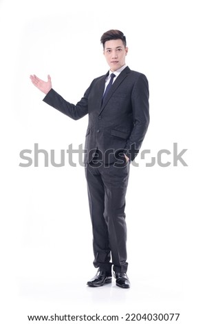 Full length portrait of a young businessman in black suit with white shirt ,tie with welcome gesture standing on white background