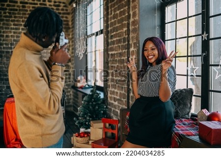 Cheerful young man and woman taking photo at home decorated for Christmas winter holiday. Happy family training together at home. Photography hobby