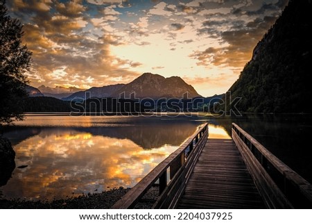 Breathtaking view of a jetty on the alpine Altausseer See (Lake Aussee) in Ausseer Land, Styria, Austria, with a stunning sunset in the background Royalty-Free Stock Photo #2204037925