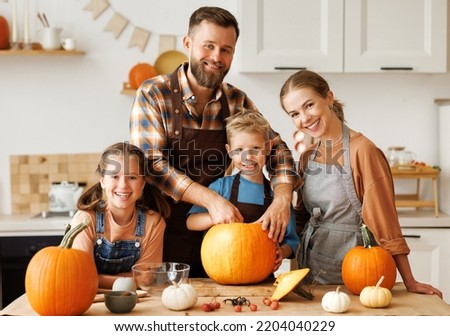 Happy family mother, father  and children daughter and son to remove   pulp from pumpkin while carving jack o lantern with family in cozy kitchen at home, parents with kids preparing for Halloween Royalty-Free Stock Photo #2204040229