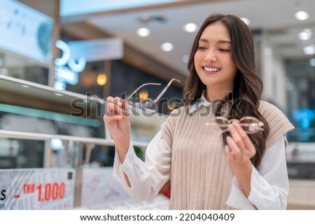 Attractive asia Young adult female woman casual cloth spending weekend vacation enjoy choosing glasses in optical store shop she is pick the favourite one for herself Royalty-Free Stock Photo #2204040409