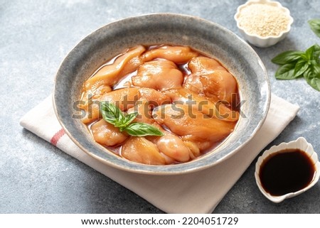 Raw diet marinated chicken meat with teriyaki sauce in a grey bowl. Marinating meat for cooking barbecue Royalty-Free Stock Photo #2204051729