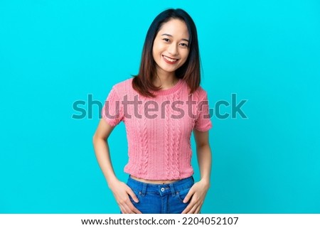 Young Vietnamese woman isolated on blue background laughing