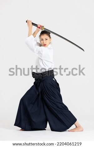 Aikido master woman in traditional samurai hakama kimono with black belt with sword, katana on white background. Healthy lifestyle and sports concept. Royalty-Free Stock Photo #2204061219