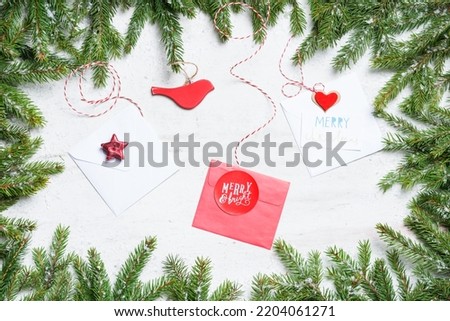 Frame of fir tree branches with snow and Christmas envelopes, wooden bird, candle in middle on bright painted background.  New Year and Christmas concept. Top view