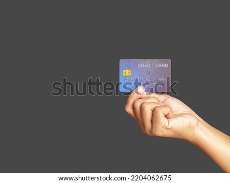 Hand of holding a mockup blue credit card while standing with gray background in the studio. Close-up photo. Money and business concept