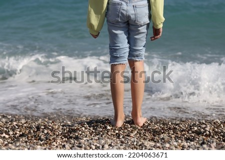 Children feet barefoot on pebble beach near sea. Feet of child in water and holiday and rest of children sea