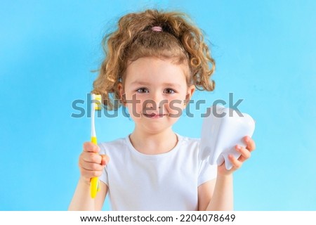 smiling girl holding tooth dent and toothbrush. Kid training oral hygiene. creative medical dental dentistry sromatology. Child learning brushing, cleaning teeth. Prevention of caries. dental kids Royalty-Free Stock Photo #2204078649
