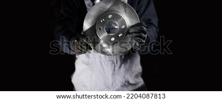 concept of replacing car brake discs. Brake disc in the hands of a master on a dark background, repair of the brake system