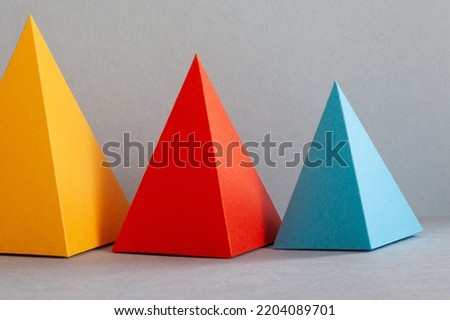 Abstract geometrical minimalism. Three-dimensional prism pyramid objects on gray background. Yellow red blue colored solid figures