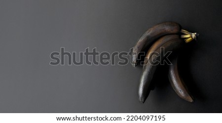 Bananas with a blackened peel on a dark background. Monochrome. Minimal composition. Modern design poster