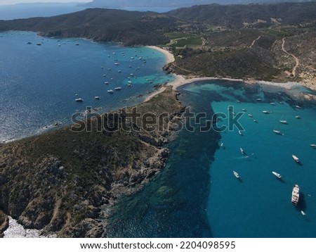 Aerial view of Plage Ranc and Cap Taillat in French Riviera, near Saint-Tropez. Beautiful rocky beach near coastal path with luxury yachts, turquoise and idyllic water. Drone view from above France.