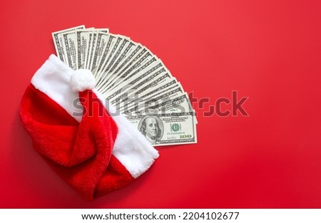 One hundred dollar bills inside Santa hat on red background. Concept of Christmas or New Year's gift, winning, annual income. Copy space, flat lay.