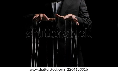 Man hands with strings on fingers on black background. Violence, harassment, bullying concept. Master in business suit, abuser using influence to control person behavior. Manipulation of government. Royalty-Free Stock Photo #2204103315
