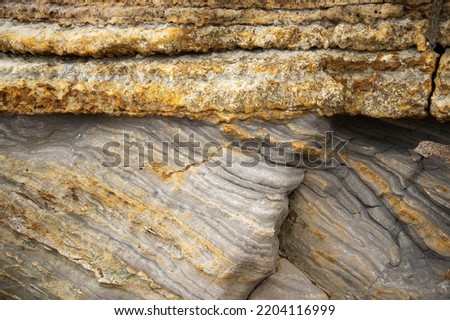 This Jurassic sedimentary strata shows a feature known as an Unconformity. The underlying darker mudstones have been tilted and then the overlaying sandstones deposited on a horizontal plane Royalty-Free Stock Photo #2204116999